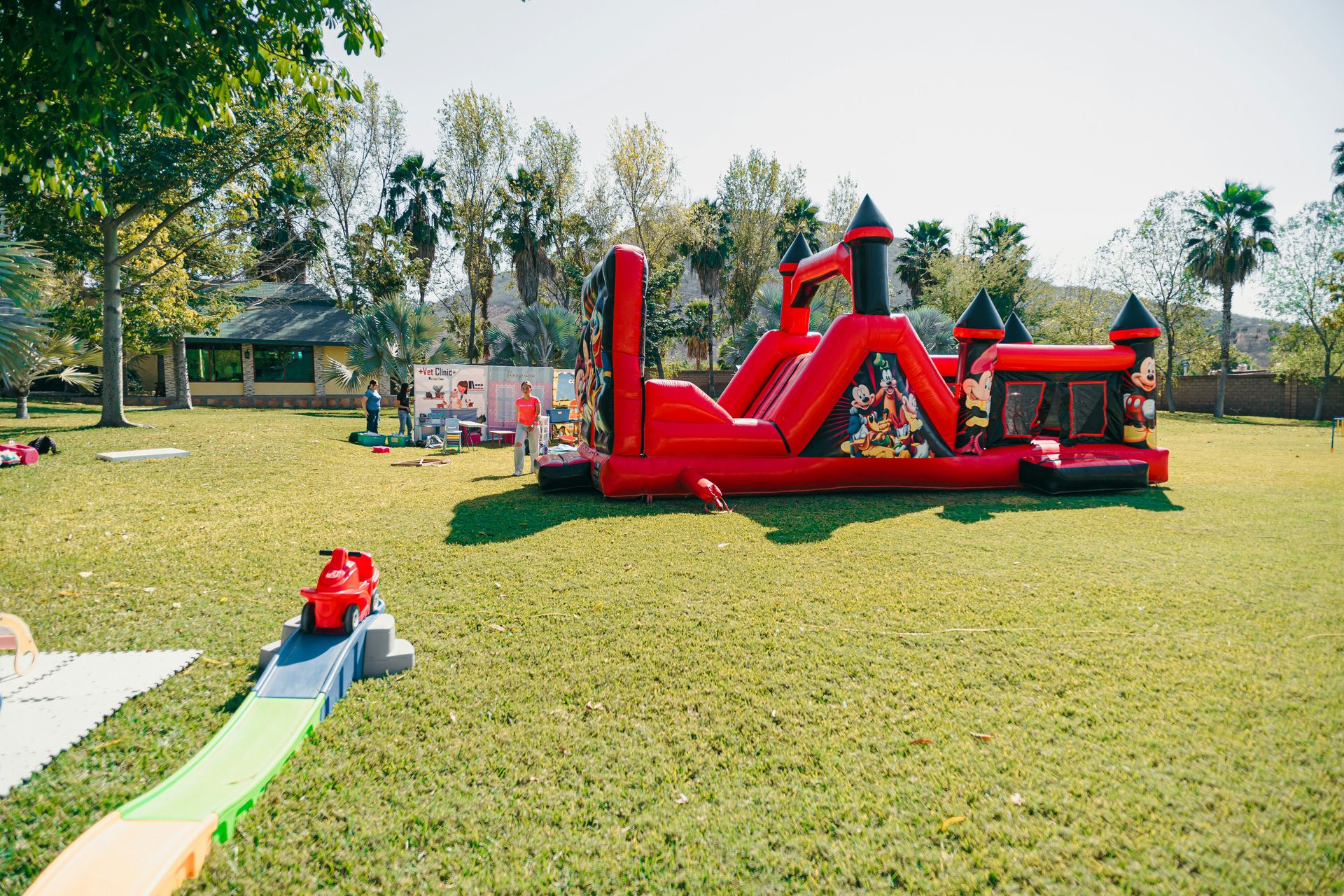 A red inflatable castle bounce house on a grassy lawn.