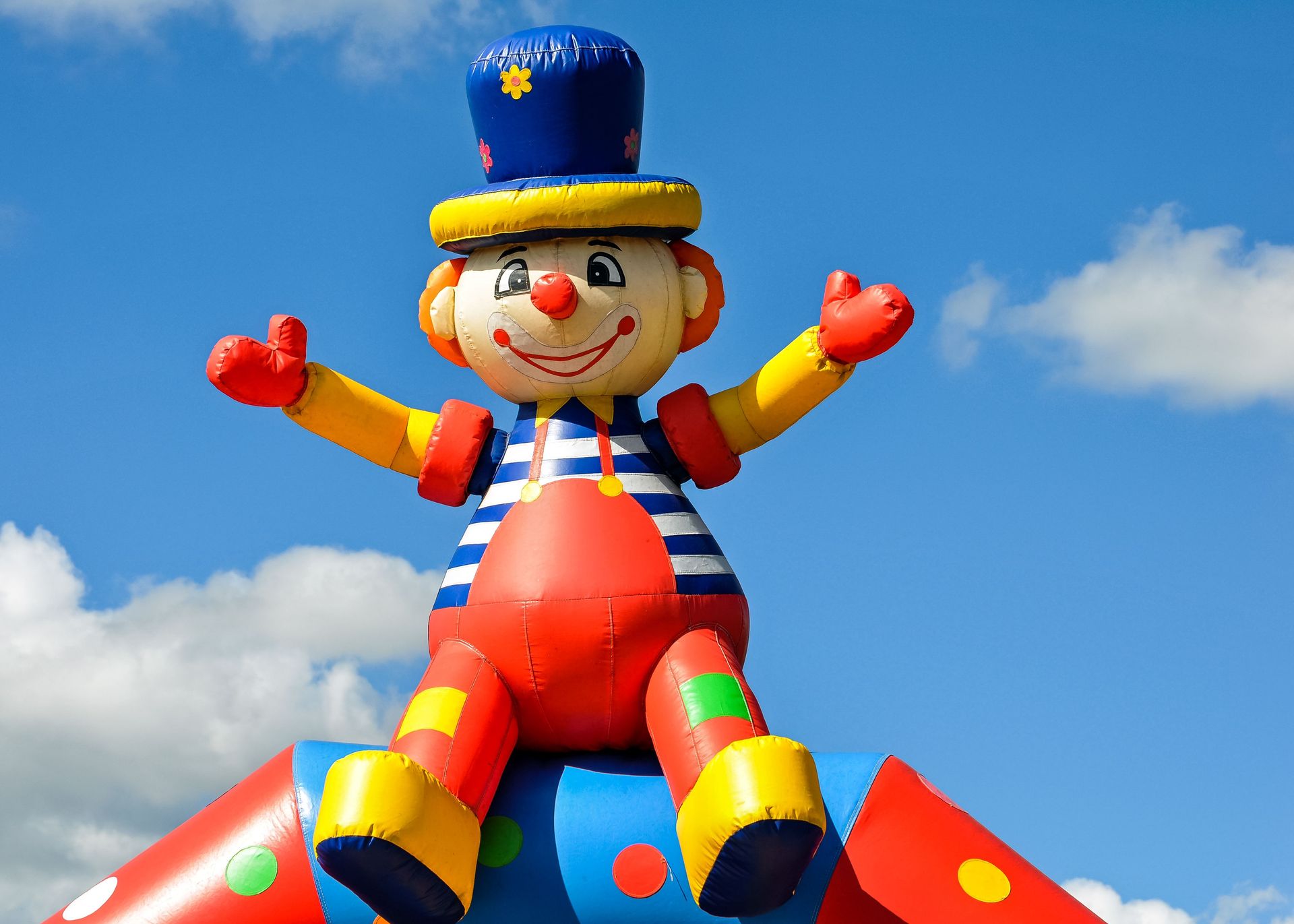 A vibrant inflatable clown at an outdoor carnival under a bright blue sky, symbolizing fun and joy.
